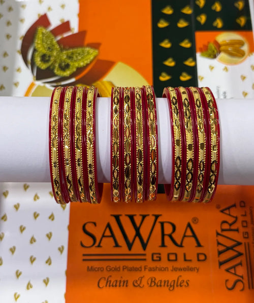 A set of red and gold chain bangles displayed on a white cylindrical stand, with a branded orange and white SAWRA GOLD box in the background.